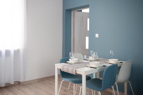 a dining room with a white table and blue chairs at Apartamenty Emilia 2 in Gniezno