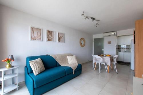 un salon avec un canapé bleu et une table dans l'établissement Studio Pampa Plage Terrasse Beau volume Pied dans l'eau, à Mauguio
