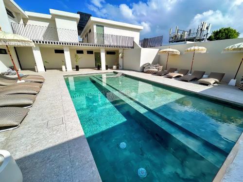 聖胡安的住宿－Bali Poshtel PR，房屋旁的游泳池配有椅子和遮阳伞