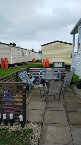 a patio with chairs and a table in a yard at Caravan at Seton Sands in Port Seton