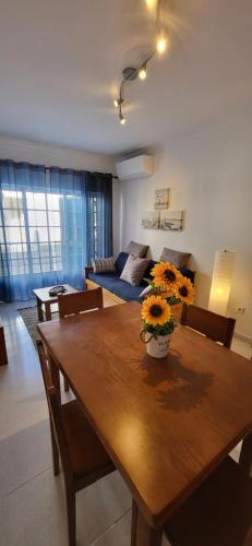 - un salon avec une table en bois et des fleurs dans l'établissement Apartamento Sunrise, à Altura