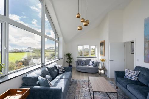 a living room with blue couches and large windows at Bay View Villa in Carbis Bay