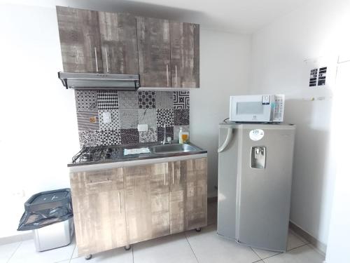 a small kitchen with a sink and a refrigerator at PARK 2009 Apartaestudios in Cali