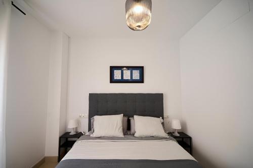 マラガにあるApartamento Málaga Centroのベッドルーム1室(白い壁のベッド1台、シャンデリア付)