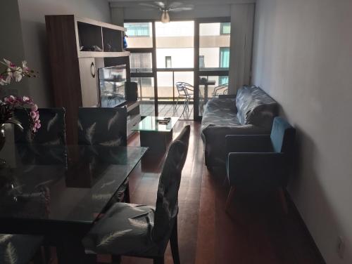 ein Wohnzimmer mit einem Sofa und einem Glastisch in der Unterkunft Recreio, a praia mais charmosa do RJ! in Rio de Janeiro
