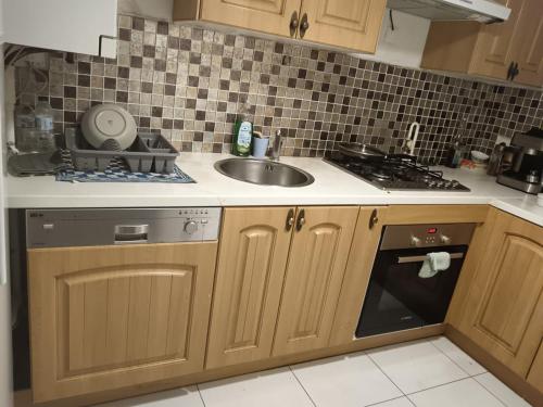 une cuisine avec des armoires en bois, un évier et une cuisinière dans l'établissement Appartement proche de Disneyland, à Bussy-Saint-Georges