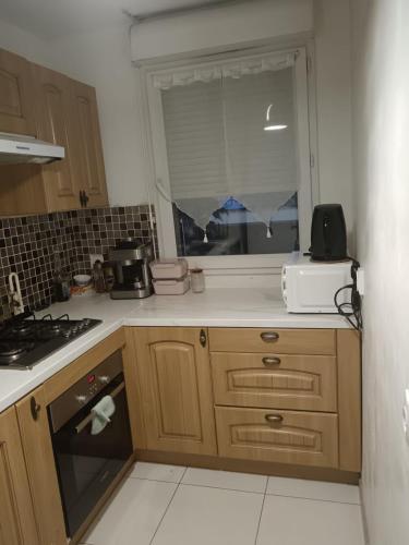 une cuisine avec un évier, une cuisinière et une fenêtre dans l'établissement Appartement proche de Disneyland, à Bussy-Saint-Georges