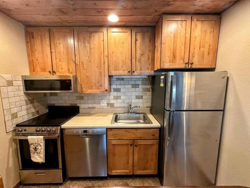 a kitchen with wooden cabinets and a stainless steel refrigerator at Winter Haus, Winter Park 2 bedrooms corner unit w outdoor patio walking distance to the Center of town in Winter Park