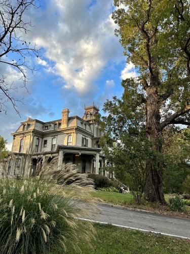 a large house with a tree in front of it at Garth Woodside Mansion Bed and Breakfast in Hannibal