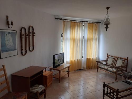 sala de estar con mesa, silla y TV en Ivanovino Residence, en Varna