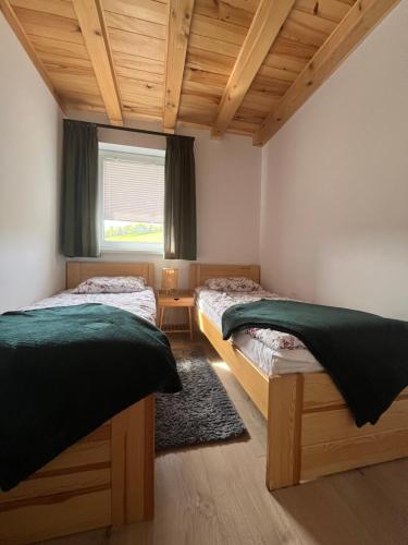 two beds in a room with a window and wooden ceilings at Biesiedlisko Bieszczadzkie in Polańczyk