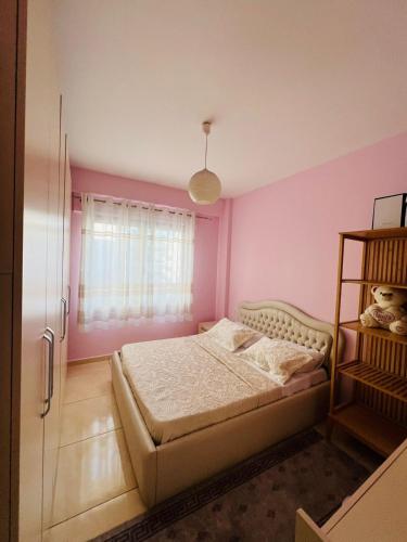 a bedroom with a bed and a pink wall at KRISTO Apartment-Tirane in Tirana