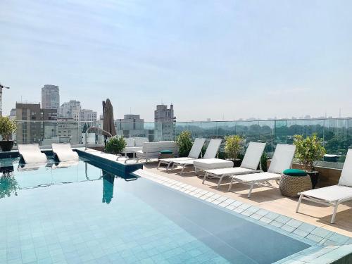 a swimming pool with chairs and a view of a city at Ap Moema próx parque Ibirapuera cd 504 sint in São Paulo