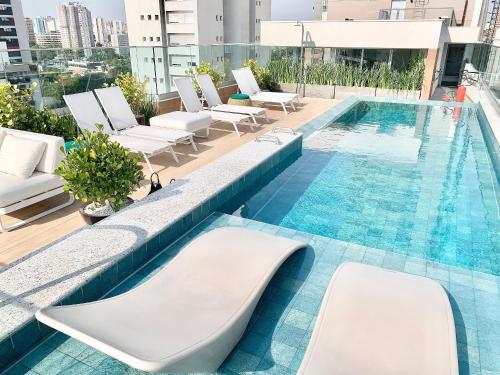 a pool on the roof of a building with white lounge chairs at Ap Moema próx parque Ibirapuera cd 504 sint in São Paulo