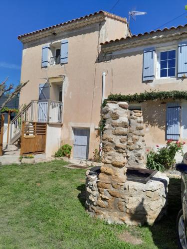 une maison avec un mur en pierre devant elle dans l'établissement thym & Romarin, à Aubignan