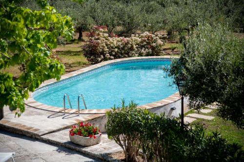 una piscina en un jardín con flores y árboles en Masseria Trulli Bruni, en Locorotondo