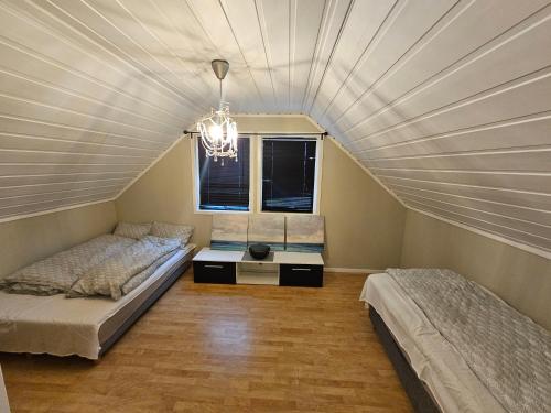 een slaapkamer op zolder met 2 bedden en een kroonluchter bij Hjem i Sørumsand 25 min fra Gardermoen 