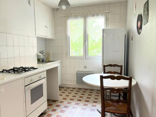 une cuisine avec un réfrigérateur et une table à l'intérieur dans l'établissement Magnifique Appart - 2 Chambres proches du centre - Calme & Tout Equipé, à Grenoble