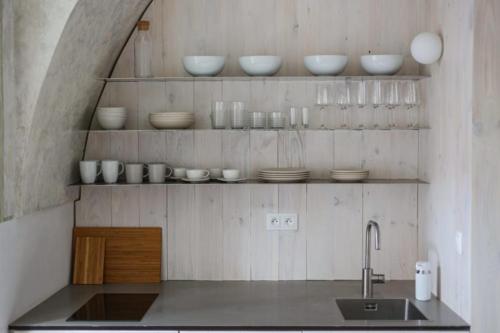 uma cozinha com um lavatório e tigelas nas prateleiras em Ubytovanie v Kláštore - Apartmány em Rožňava