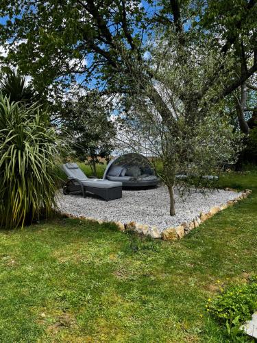 a garden with a couch and a tree and grass at Le Vieux Renard in Vieux-Ruffec