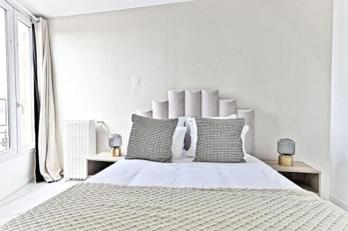 - une chambre blanche avec un grand lit et des oreillers noirs et blancs dans l'établissement Appartement lumineux et moderne - Gagny, à Gagny