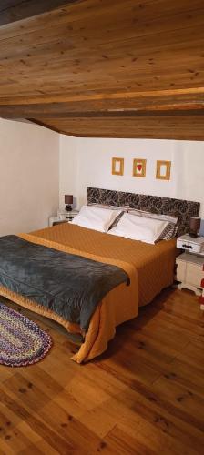 a large bed in a bedroom with a wooden ceiling at Um quarto da Casa Do Monte in Água de Alto