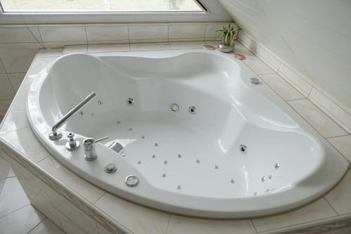 a white bath tub in a bathroom with a window at Ferienhaus direkt an der Spree mit Whirlpool und Sauna in Berlin