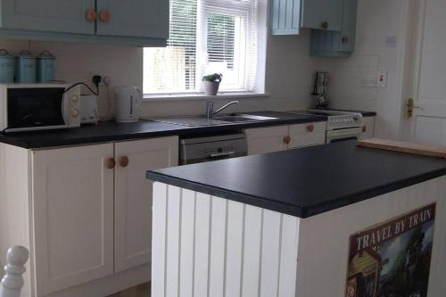 a kitchen with white cabinets and a black counter top at Moor House in Gorey