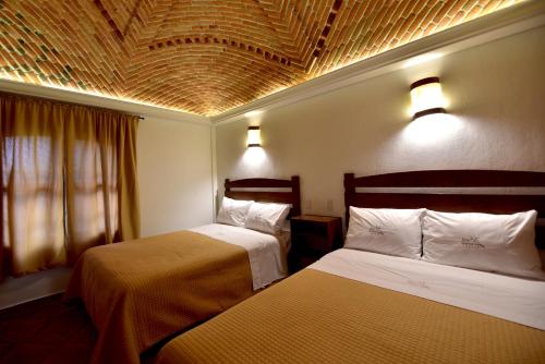 a hotel room with two beds and a ceiling at Hotel Santa Irene in Cholula