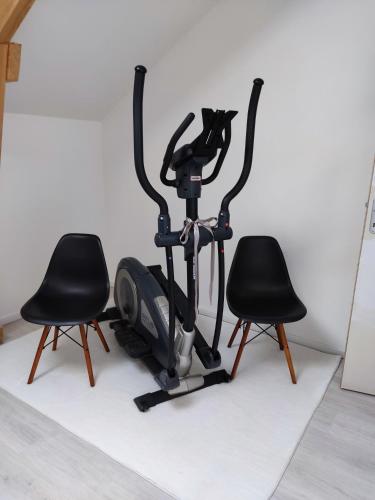a gym with two black chairs and a exercise bike at Chambre spacieuse, jacuzzi, proche parc Astérix in Thiers-sur-Thève