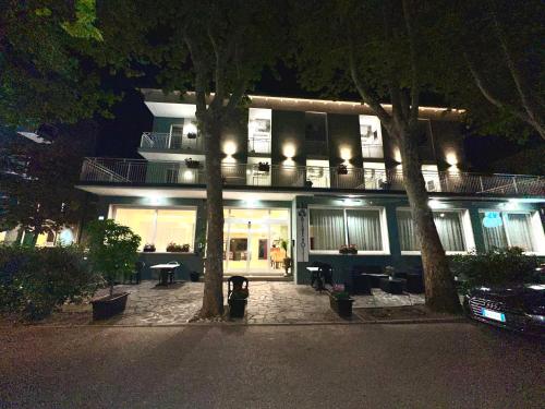 a building at night with trees in front of it at Blue Loft Hotel in Cesenatico