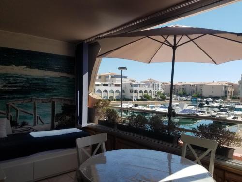 une table avec un parasol et une vue sur une marina dans l'établissement Sète Marina des Quilles, grand T2 climatisé, proche plage, parking privé, à Sète