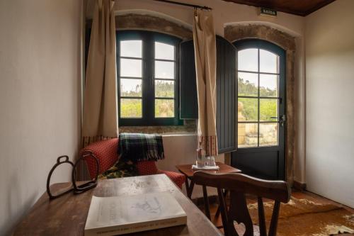 a room with a table and two windows at Quinta do Brejo - Turismo Equestre in Mafra