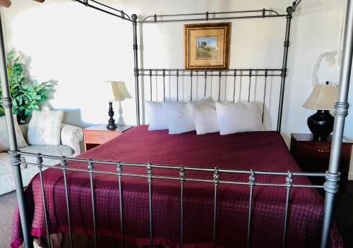 a bedroom with a canopy bed with a red comforter at Cottonwood Court Motel in Santa Fe