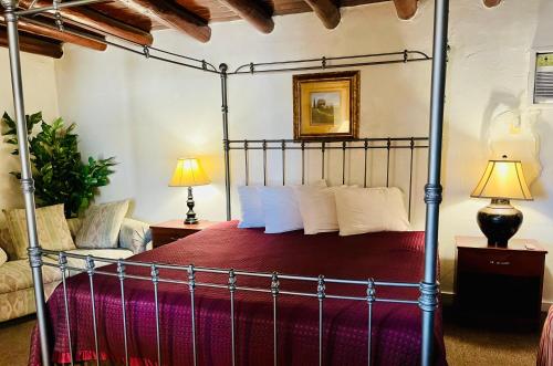 1 dormitorio con cama con dosel y colcha roja en Cottonwood Court Motel en Santa Fe