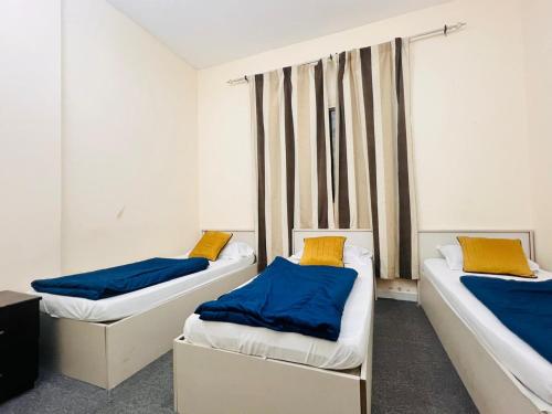 two beds with blue and yellow pillows in a room at Short Term Tourist Place in Dubai