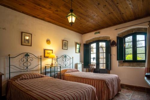 two beds in a room with two windows at Quinta do Brejo - Turismo Equestre in Mafra
