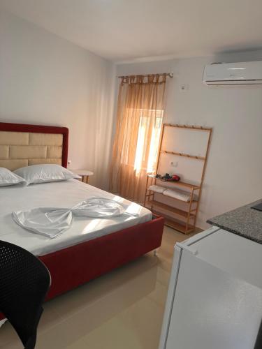 ein Schlafzimmer mit einem Bett in einem Zimmer mit einem Fenster in der Unterkunft Andi's GuestHouse in Sarandë