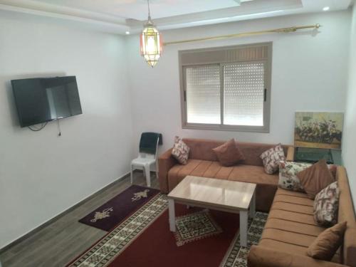 een woonkamer met een bank en een tv bij appartement proche de la mer in Agadir