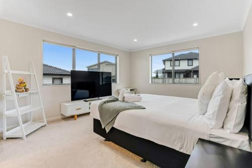 una camera bianca con un grande letto e una grande finestra di 5 BDR Flat Bush Mansion - Central Aircon, Fast WiFi, Pool Table, Netflix and More! ad Auckland