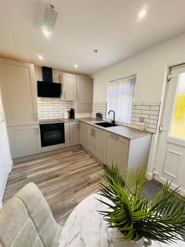 a kitchen with white cabinets and a sink and a couch at Newly Renovated Private self contained room with Private dedicated Bathroom - Selly Oak Birmingham R2 in Birmingham