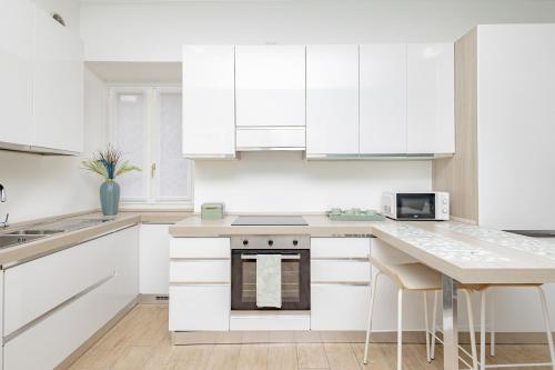 a white kitchen with white cabinets and a table at Manzoni in Lecco