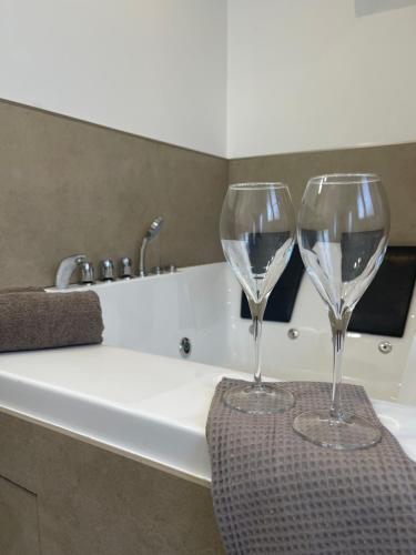 2 verres à vin assis au-dessus d'une baignoire dans l'établissement L’Harmonie - suite balneo, à Gournay-en-Bray