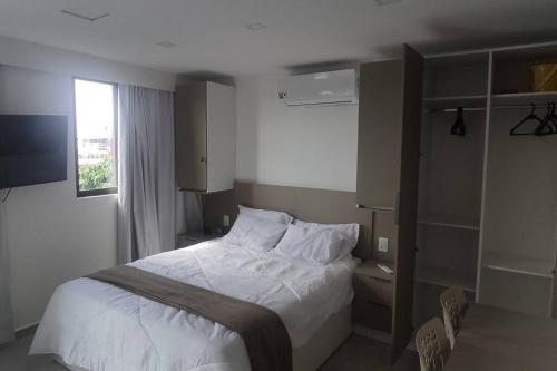 Un dormitorio con una cama con sábanas blancas y una ventana. en Flat 305 Porto Prime com Rooftop e Piscina, en Porto de Galinhas
