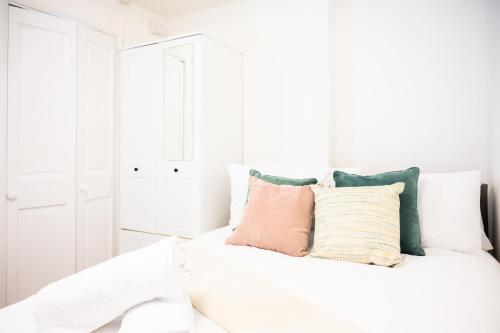 um quarto branco com uma cama branca com almofadas em Northern Hideaways, Lockup Mews em Bellingham