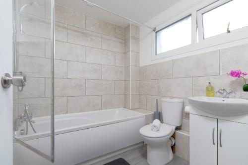 a white bathroom with a tub and a toilet and a sink at Newly refurbed, 5BR, Sleeps 12 in Northampton