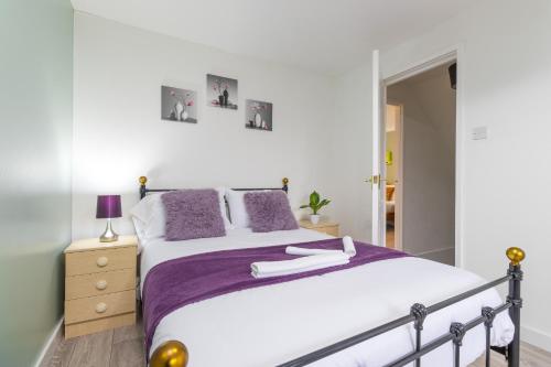 a bedroom with a large bed with purple pillows at Newly refurbed, 5BR, Sleeps 12 in Northampton