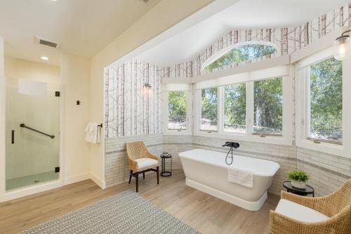 a bathroom with a white tub and windows at Rancho Robles by AvantStay Vineyard Villa w Views Pool Privacy in Paso Robles