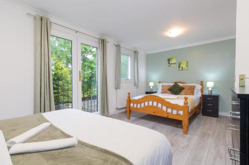 a bedroom with two beds and a large window at Newly refurbed, 5BR, Sleeps 12 in Northampton