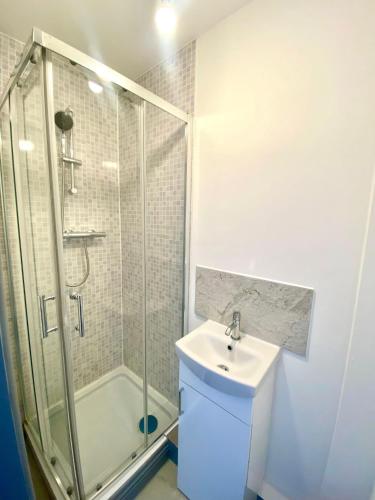 La salle de bains blanche est pourvue d'une douche et d'un lavabo. dans l'établissement Gillingham Gem : Cozy Rooms, à Gillingham